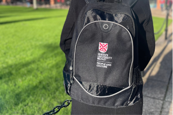 Image shows a member of staff wearing a branded People and Culture backpack